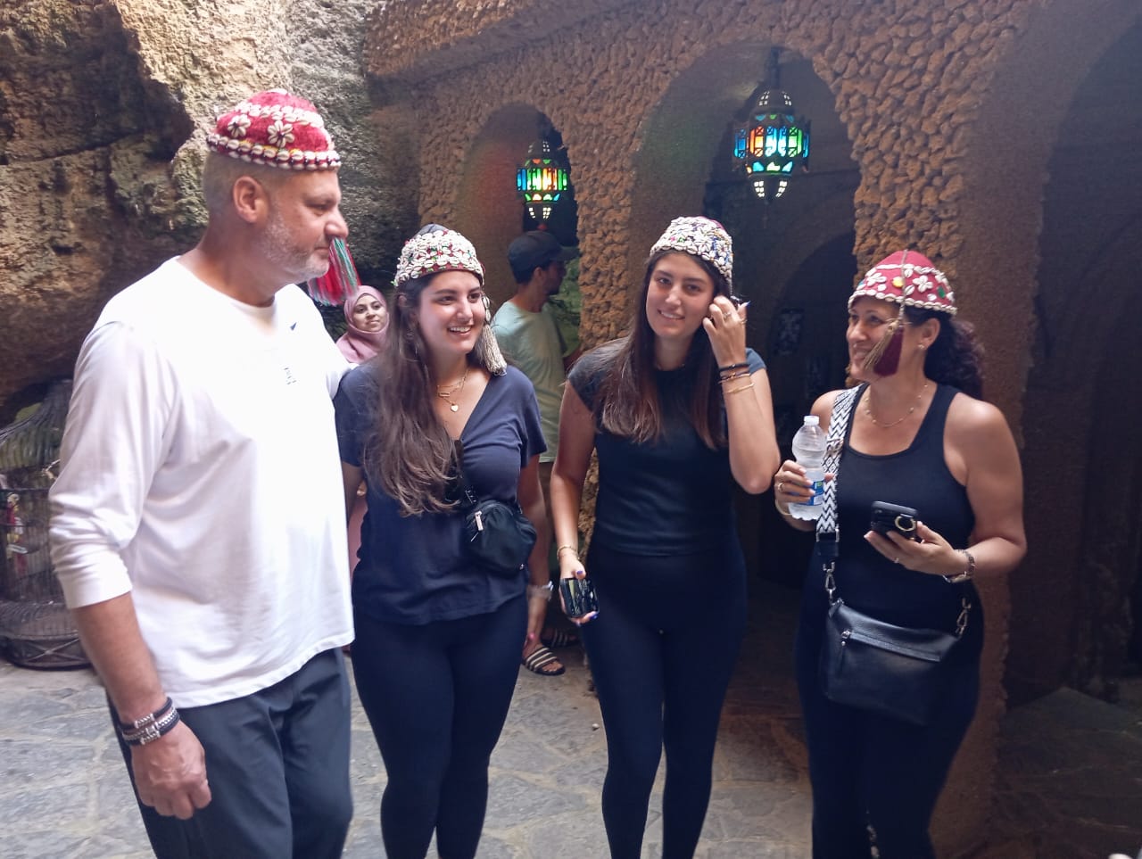 Guests trying on traditional Moroccan hats in a medina archway